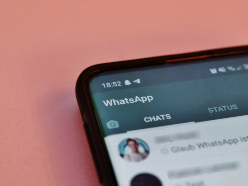 На фото смартфон на бежевом фоне с открытым мессенджером WhatsApp
